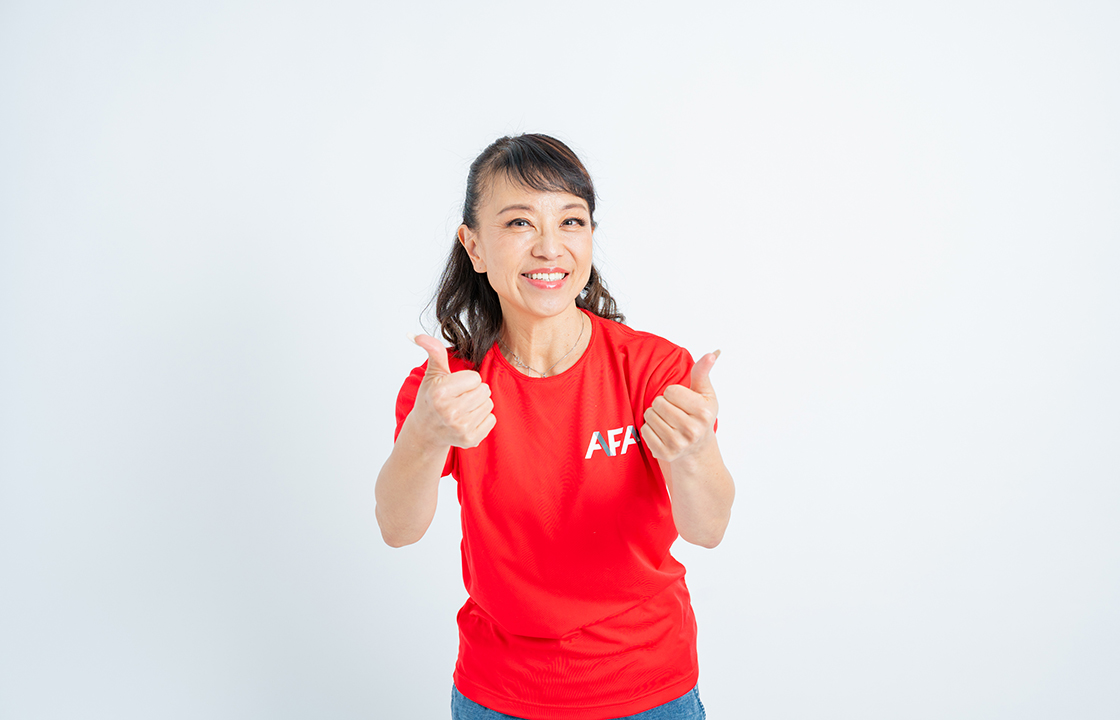 赤いTシャツを着た女性が親指を立ててダブルグッドポーズをしている様子